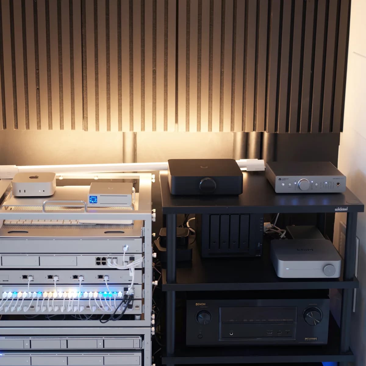 The room the site is written from: a UniFi rack against a slatted wall under a filament bulb.