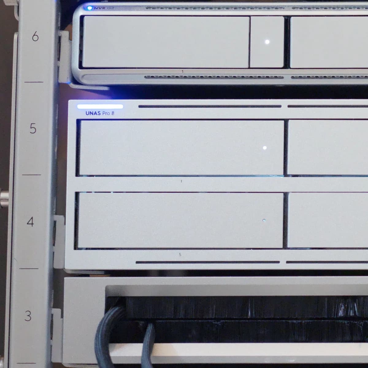 A UNAS Pro 8 at U4 and U5 of a UniFi rack, its front panel labelled, below a 1U recorder and above a brush panel.