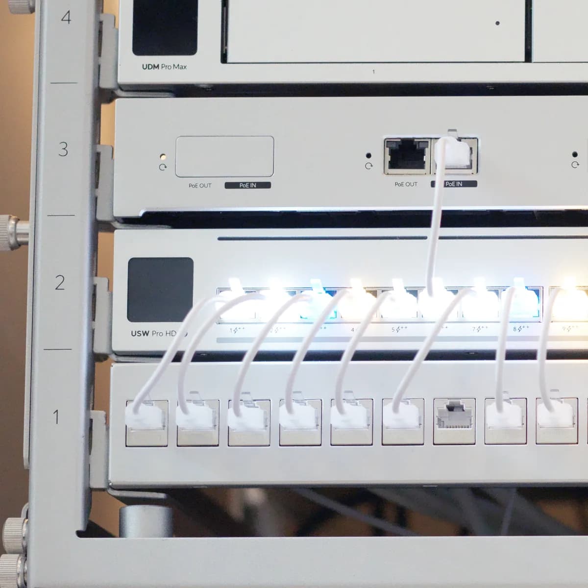 A USW Pro HD at U2 of a UniFi rack, its front panel labelled, ports lit and patched in white to the panel below.