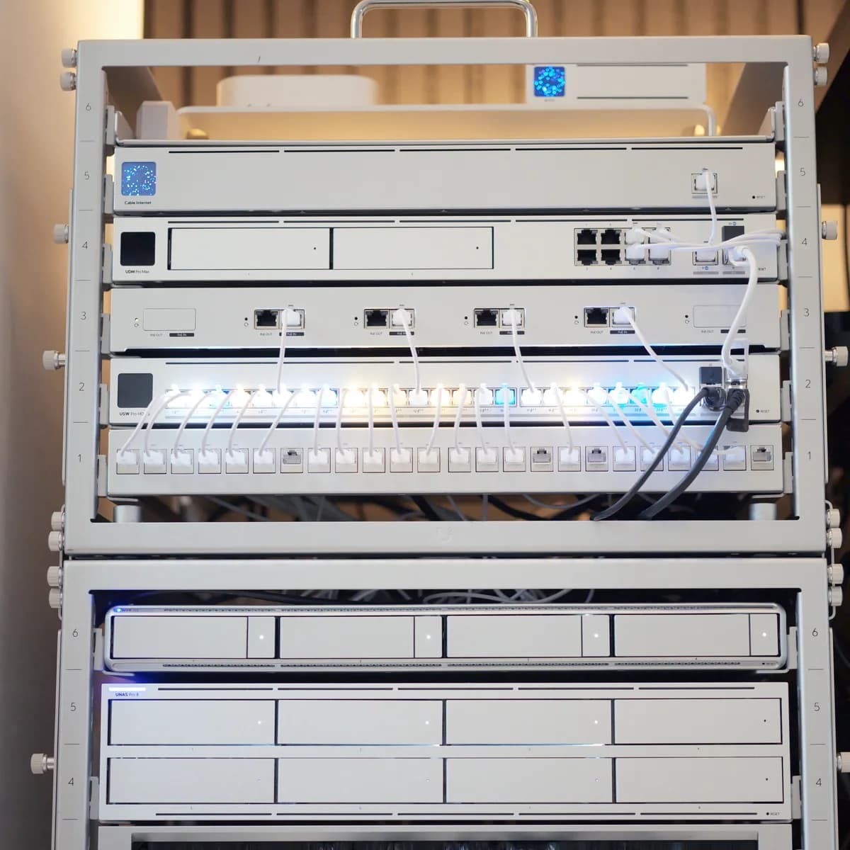 A UniFi rack: gateway, PoE panel, switch and patch panel above a network video recorder and NAS.