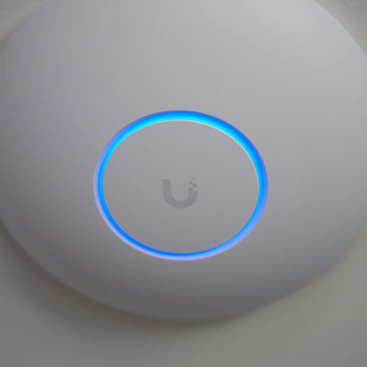 A U7 Pro Max mounted on a ceiling, its status ring lit blue around the Ubiquiti mark.